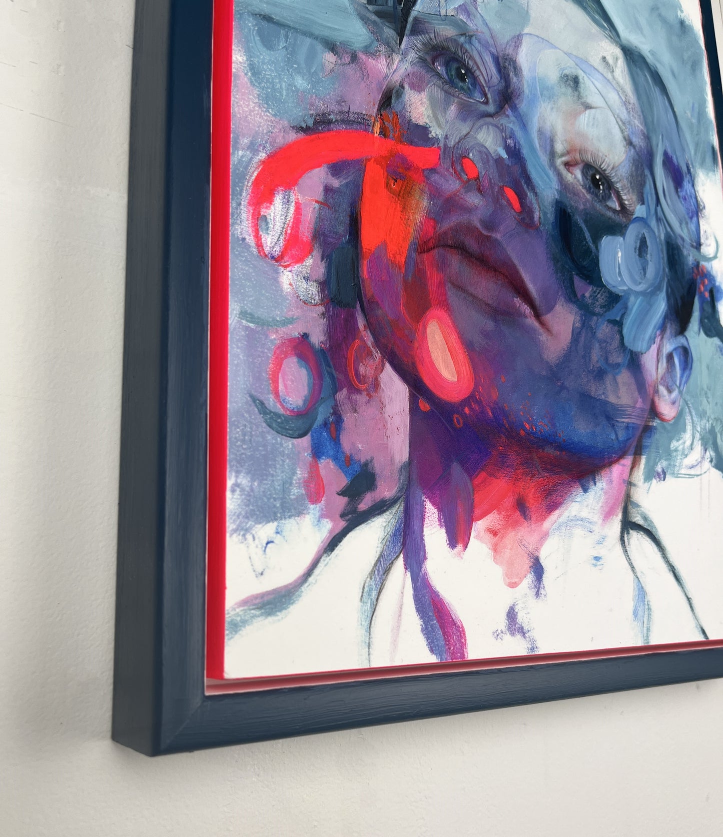 Image of side of framed artwork, blue frame, hanging on white wall