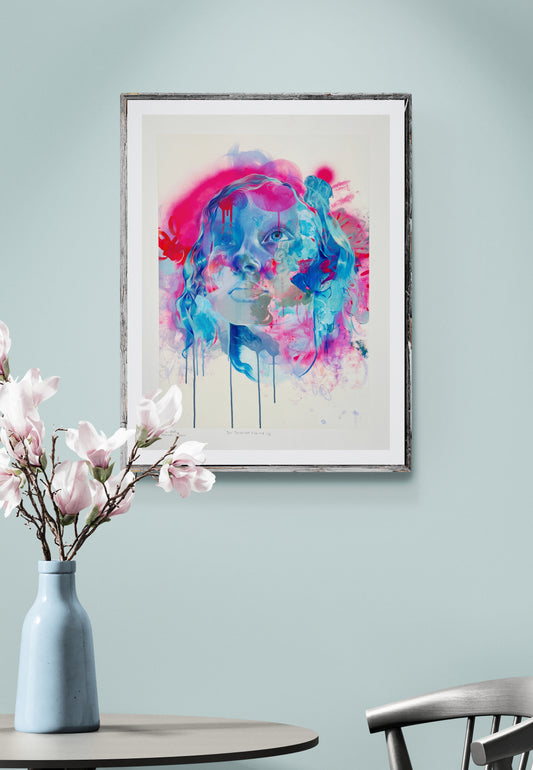 Framed image of pink blue art on pale green wall with table, chair and vase with flowers