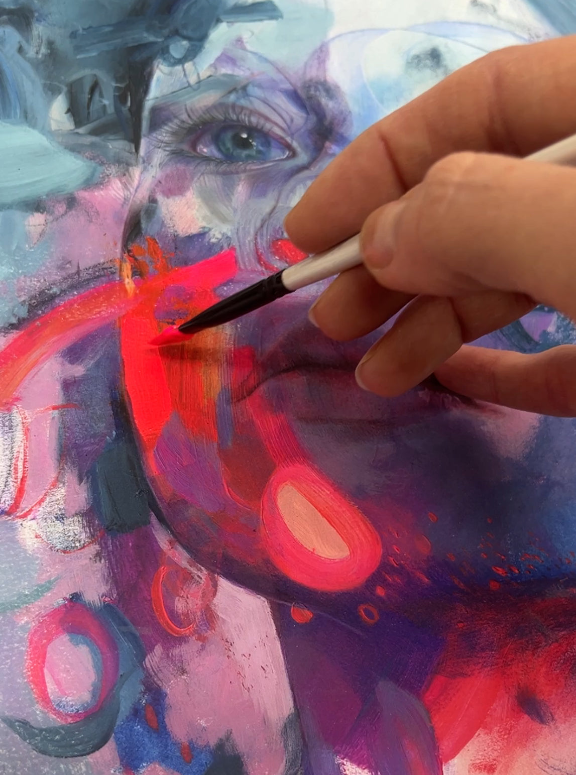 Photo of hand holding paintbrush adding paint to artwork